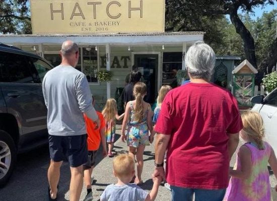 Two Adults And Many Children Walking Toward Hatch Cafe And Bakery
