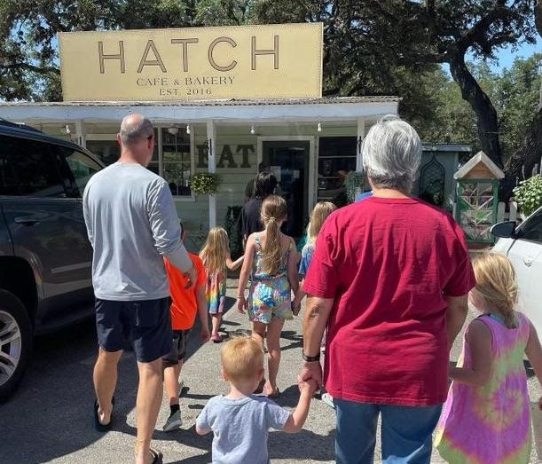 Two adults and many children walking toward Hatch Cafe and Bakery
